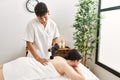 Man massaging woman back using massage gun percusion at beauty center Royalty Free Stock Photo