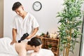 Man massaging woman back using massage gun percusion at beauty center Royalty Free Stock Photo