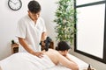 Man massaging woman back using massage gun percusion at beauty center