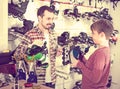 Man master fixing roller-skates for boy in sports store