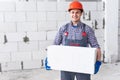 Young man, master mason holding a large block of aerated concrete