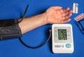 Man measures blood pressure on a blue medical table. Take care of your own health. The digital blood pressure monitor shows good