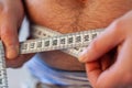 Man measures her abdomen with a measuring tape