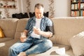 A man measures his blood pressure at home with a cuffed blood pressure monitor and records his results on his phone