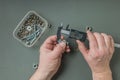 A man measures a metal bolt with an electronic caliper