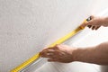 Man measuring baseboard indoors, closeup.