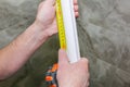 Man is measuring gypsum baseboard. Maintenance repair works renovation in the flat. Drywall panel Royalty Free Stock Photo