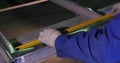 A man measuring a part to make sure of the width before cutting it. a worker measures the frame for the window. Employee