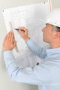 Man measuring plans pinned to wall