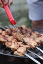 Man measuring temperature of delicious kebab on metal brazier outdoors, closeup