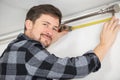 Man measuring under curtain rail Royalty Free Stock Photo
