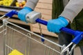 A man in medical gloves holds a grocery cart, close-up. No face visible