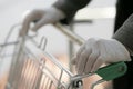 A man in medical gloves holds a grocery cart, close-up, no face