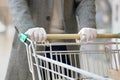 A man in medical gloves holds a grocery cart, close-up, no face