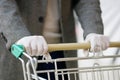 A man in medical gloves holds a grocery cart, close-up, no face