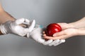 A man in medical gloves is injected chemical into the fruit of a peach, lying in the hands of a woman. The concept of GMO products Royalty Free Stock Photo