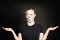 Man in medical mask holding empty open hands on blackboard. Choice and capability concept