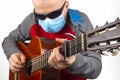 Man in a medical mask plays the classical guitar on a white background. musical creativity. string musical instrument