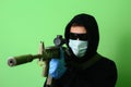 Man in a medical mask and sunglasses dressed in black clothes with a hood holds an automatic assault weapon Royalty Free Stock Photo