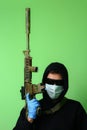 Man in a medical mask and sunglasses dressed in black clothes with a hood holds an automatic assault weapon Royalty Free Stock Photo