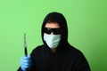 Man in a medical mask and sunglasses dressed in black clothes with a hood holds a knife in his hand Royalty Free Stock Photo