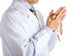 Man in medical white coat holding wooden Rosary beads