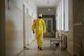 A man - a medical worker or a doctor in a yellow suit of bacterial and chemical protection is walking along the corridor of an old