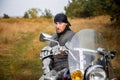 man in medieval knight's armor with a bandana on his head sits on a motorcycle against the backdrop of the forest