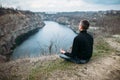 Man meditating on rocky cliff with river view Royalty Free Stock Photo
