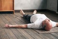 Man meditating on a wooden floor and lying in Shavasana pose after practice Royalty Free Stock Photo