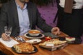 Man with menu in a restaurant taking order at table Royalty Free Stock Photo