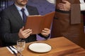 Man with menu in a restaurant taking order at table Royalty Free Stock Photo