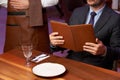 Man with menu in a restaurant taking order at table Royalty Free Stock Photo