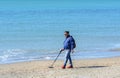 A man with a metal detector is looking for expensive jewelry lost in the sea. A man walks along the beach in search of jewels