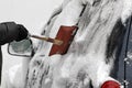 A man with a metal shovel cleans car from snow on the street after big snowstorm in the city, all cars under snow, icy roads, snow Royalty Free Stock Photo