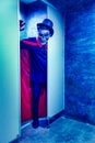 A man with metal skull mask and red cloak in blue light toilet in halloween party