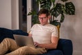 Man middle aged student working on educational project lying on couch at home in evening after job.