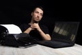 Man midway between a typewriter and laptop on black background in low key.The concept of the past and the future Royalty Free Stock Photo