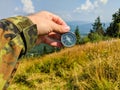 Man in military clothes holding a compass in a hand on the carpathian mountains background