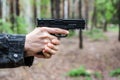 A man in military clothing is aiming a pistol.