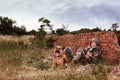 Man in military with German shepherd dog near broken brick wall