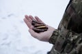 A man in military uniform holds several machine gun shells in his hand.