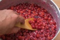 A man mixes a wooden spoon cherry jam. Royalty Free Stock Photo