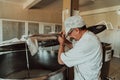 Man mixing milk in the stainless tank during the fermentation process at the cheese manufacturing