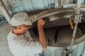 Man mixing milk in the stainless tank during the fermentation process at the cheese manufacturing