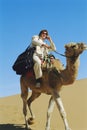 Man with mobile phone riding camel in desert Royalty Free Stock Photo