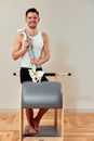 A man with a model of the spine in his hands during a Pilates reformer class, a young man shows how the spine bends when