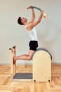 A man with a model of the spine in his hands during a Pilates reformer class, a young man shows how the spine bends when