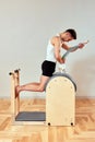 A man with a model of the spine in his hands during Pilates on the reformer. A young man shows how the spine bends when