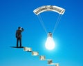 Man on money stairs looking light bulb with money parachute Royalty Free Stock Photo